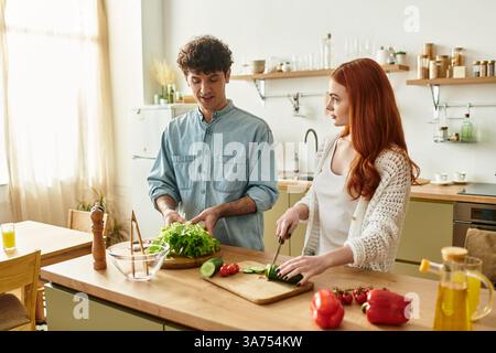 La giovane coppia condivide un momento delizioso mentre preparano un pasto fresco insieme a casa. Foto Stock