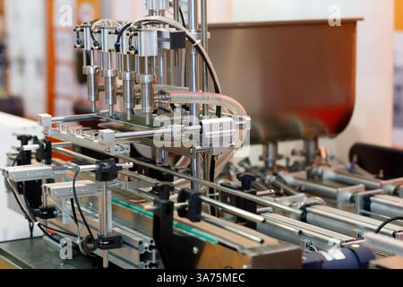 Linea di trasporto con riempitrice automatica di bottiglie. Messa a fuoco selettiva. Foto Stock