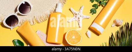 Vacanze estive, protezione UV. Crema solare arancione, occhiali da sole, cappello di paglia su sfondo giallo, striscione. Prodotti cosmetici SPF per la protezione solare. Foto Stock