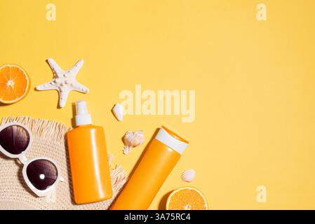Modello da spiaggia estivo con occhiali da sole, stelle marine, prodotti per la crema solare, cappello di paglia, conchiglie di mare su sfondo giallo, vista dall'alto, spazio fotocopie. Estate stagionale Foto Stock