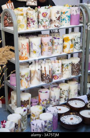 Uno stand con candele aromatiche firmate fatte di cera bianca e bellissimi fiori secchi, fatti a mano Foto Stock