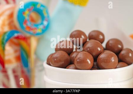 Caramelle. Dolci al cioccolato in tazza di carta su sfondo sfocato, primo piano Foto Stock