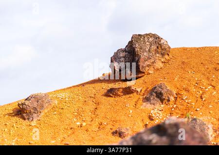 Formazione rocciosa di bauxite erosa con colori arancio brillanti in una miniera di bauxite abbandonata Foto Stock