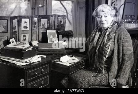 Anni '1930, storica, la signora Cecilia Nina Bowes-Lyon, Contessa di Strathmore e Kinghorne GCVO seduta alla sua scrivania circondata da foto incorniciate di membri della famiglia. Membro della nobiltà britannica, era la madre della regina Elisabetta (la regina madre) e nonna della regina Elisabetta II Foto Stock