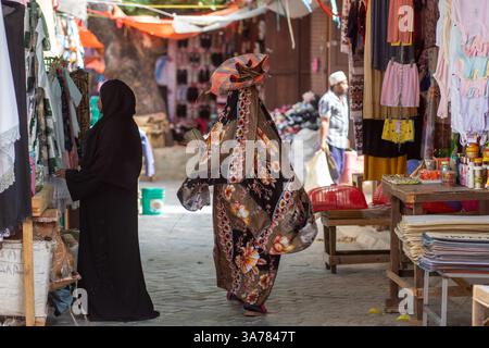 Donne in abbigliamento tradizionale che camminano attraverso un mercato locale, Zanzibar , Tanzania Foto Stock