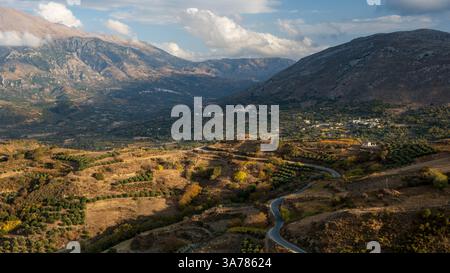 Una strada tortuosa serpeggia attraverso il paesaggio montuoso di Creta, Grecia, collegando piccoli villaggi annidati nelle valli. La strada fornisce l'accesso f Foto Stock