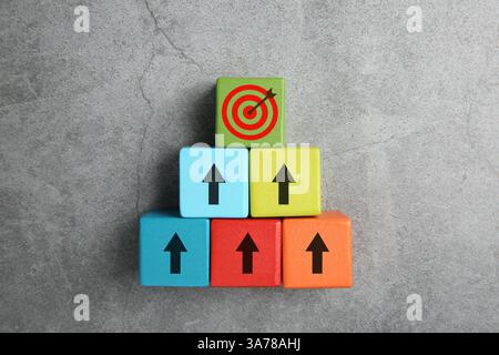 Targeting. Cubi con frecce che puntano verso il verde con un mirino su sfondo grigio, vista dall'alto Foto Stock