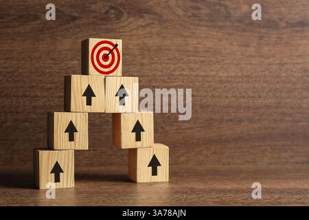 Targeting. Piramide di cubi con frecce che puntano ad uno con un mirino sulla parte superiore su sfondo di legno Foto Stock