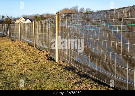 Tessuto per recinzione limosa con rete metallica e pali in legno installati prima dell'inizio della costruzione. Foto Stock