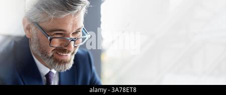 Primo piano di felice uomo d'affari di mezza età che indossa occhiali seduti in ufficio Foto Stock