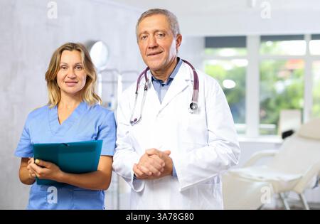 Infermiera sorridente di mezza età e medico maturo in piedi nell'armadietto del medico Foto Stock