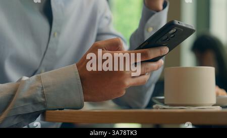 Uomo d'affari irriconoscibile cliente turista maschio visitatore ospite in caffè ristorante arabo ragazzo etnico uomo d'affari mani utilizzando l'app per telefono cellulare online Foto Stock