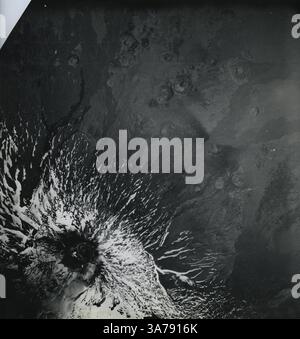 Una drammatica immagine topografica aerea dell'Etna, l'iconico stratovulcano siciliano, catturato da un aereo da ricognizione militare statunitense nell'Italia del dopoguerra. Scattata alla fine degli anni '1940, la fotografia rivela flussi lavici ricoperti di neve e fessure radiali che scendono dal cratere sommitale. Questa immagine è stata utilizzata in indagini geologiche per valutare l'attività vulcanica e il terreno sulla scia della seconda guerra mondiale Foto Stock