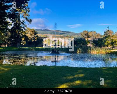 Tranquillo giardino con fontana e laghetto adagiato contro pareti di pietra e colline lontane in Irlanda. Foto Stock