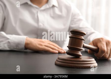 Avvocato maschile con martelletto giudice seduto al tavolo in ufficio, primo piano Foto Stock