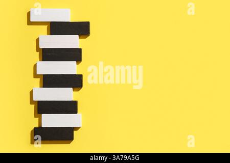Composizione con mattoni bianchi e neri su sfondo giallo Foto Stock