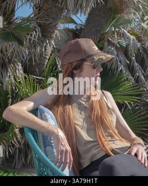Ritratto di una bella donna dai capelli rossi seduta all'aperto, luce naturale, espressione serena Foto Stock
