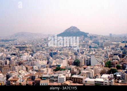 Una vista panoramica su Atene, Grecia, ripresa negli anni '1960 su pellicola slide a colori da 35 mm. Il paesaggio urbano densamente popolato si estende verso il Monte Licabetto, che si erge in modo prominente sullo sfondo. Foto Stock