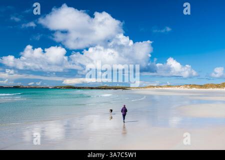 Donna che cammina con il suo cane sulla spiaggia di Triagh Thodrasdail, conosciuta come il labirinto, Isola di Tiree, Ebridi interne, Scozia Foto Stock