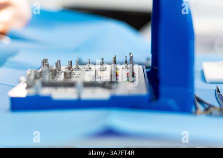 Primo piano di un kit chirurgico per impianti dentali con varie punte e strumenti disposti in un ambiente sterile. Foto Stock