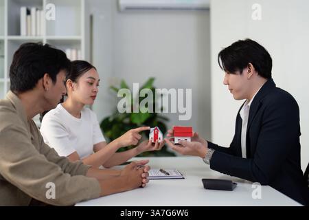 Consulenza e scelte di proprietà. Una coppia discute le opzioni abitative con il loro agente immobiliare. Foto Stock