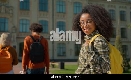 Vista posteriore da dietro amici multirazziali studenti tre ragazze donne ragazzo uomo uomo uomo uomo che cammina insieme in città vanno all'accademia universitaria Foto Stock