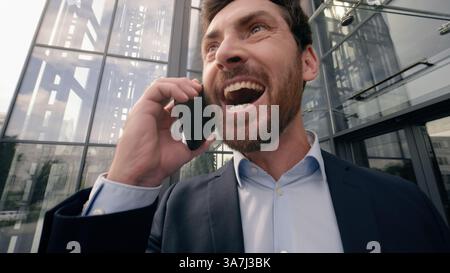 Ritratto del volto maschile manager emozionale felice eccitato in città vicino ufficio parlare chiamare cellulare condividere buone notizie eccitazione comunicare smartphone Foto Stock