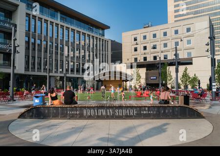Fargo, North Dakota, Stati Uniti - 12 luglio 2021: Le persone si riuniscono intorno alla fontana pubblica in una calda giornata estiva a Broadway Square mentre i bambini si raffreddano in acqua. Foto Stock