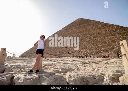 Una donna all'altopiano di Giza in Egitto, che posa di fronte alla grande Piramide. Concetto di vacanza e viaggio in Africa. Foto Stock