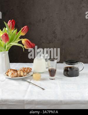 Caffè, latte e una torta con tulipani rosa sul tavolo. Foto Stock