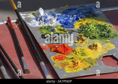 Una tavolozza con colori colorati e pennelli vari, pronta per il lavoro artistico, Provenza, Francia, Europa Foto Stock