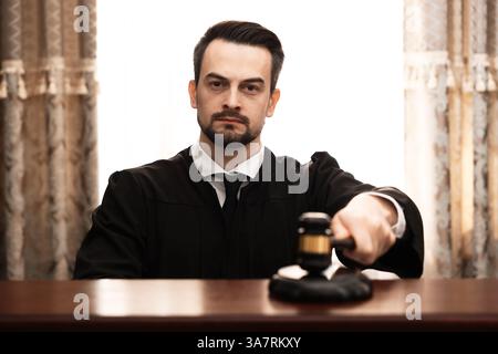 Giudice che colpisce il martelletto a tavola in aula Foto Stock