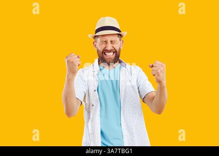 Giovane uomo felice e allegro in abiti da spiaggia casual con gesto vincente su sfondo giallo. Foto Stock
