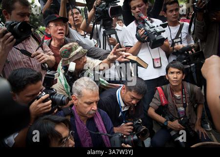 25 gennaio 2013 - Bangkok, Tailandia - i manifestanti consegnano un libro di legge per aver bruciato attraverso lo sbarramento di fotografi durante una manifestazione fuori dal Tribunale penale di Bangkok spronata dalla condanna decennale dell'editore Somyot Prueksakasemsuk per le accuse di Lese Majeste. Gli attivisti bruciarono i documenti legali e i libri di legge che chiedevano l'abolizione dell'articolo 112 e promuovevano la libertà di parola all'interno dei media. (Immagine di credito: © Hanna Adcock/ZUMAPRESS.com) Foto Stock