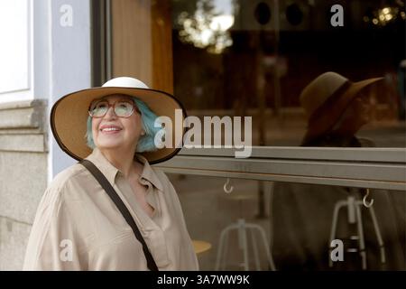 donna più anziana con cappello che cammina in città Foto Stock
