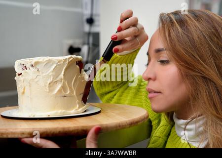 giovane pasticcere ispanico che decora una torta Foto Stock