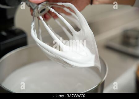 frusta elettrica in acciaio con meringa Foto Stock