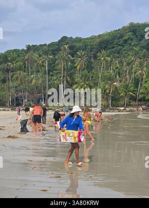 Koh Kood, Thailandia, 13 marzo 2025, gente del posto e turisti si riuniscono sulla spiaggia sabbiosa per raccogliere rifiuti e plastica Foto Stock