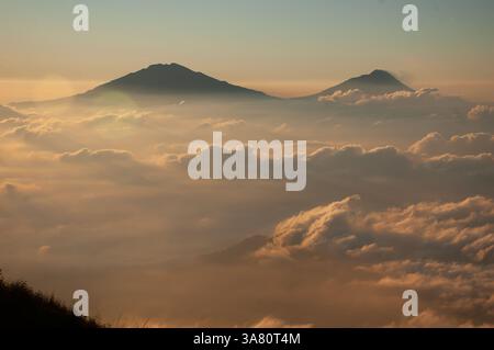 Una vista aerea mozzafiato delle vette vulcaniche che si innalzano sopra un mare di nuvole all'alba Foto Stock
