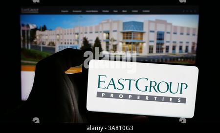 In questa immagine, una persona ha in mano un telefono cellulare con il logo della società americana REIT EastGroup Properties Inc. Sullo schermo davanti alla pagina Web. Foto Stock