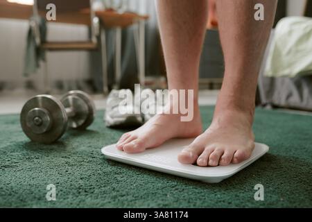Stepping on Scale in Home Gym Setting Foto Stock