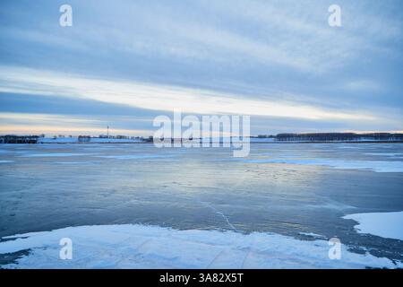 Tramonto invernale su un lago ghiacciato con turbine eoliche Foto Stock