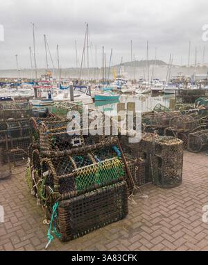 Creme e vasi di aragosta, impilati sul muro del porto, con file di barche ormeggiate e i loro alberi che si innalzano nella nebbiosa mattinata a Scarborough. REGNO UNITO Foto Stock