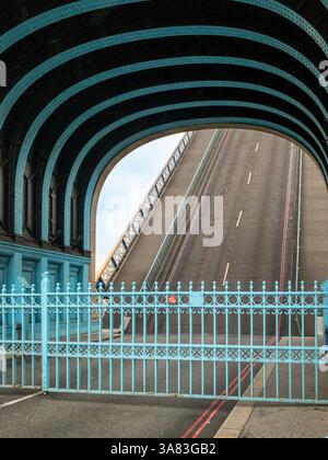 Porte blu ornate chiuse attraverso il Tower Bridge mentre la strada si solleva per consentire alle alte barche di passare sotto il fiume Tamigi. Londra. REGNO UNITO Foto Stock