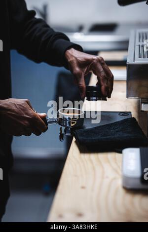 Mani di un giovane nero che prepara il caffè con una macchina per espresso Foto Stock