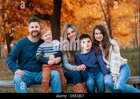 La famiglia felice si siede insieme in un bel parco il giorno d'autunno Foto Stock