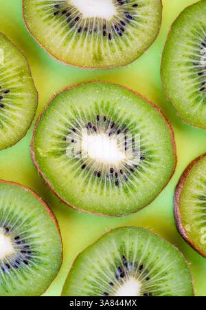 Vista dall'alto ravvicinata delle fette di kiwi su sfondo verde fisso. Foto Stock