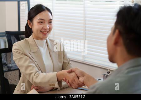 Coinvolgimento dei clienti e degli immobili. Un agente immobiliare discute i termini con un cliente durante una riunione. Foto Stock