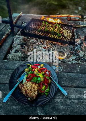 Una piacevole serata estiva in una vacanza in campagna. Una griglia a legna su cui sono state cucinate le verdure, un piatto nero con verdure colorate Foto Stock