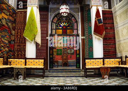 Scopri gli interni con pile di vivaci tappeti marocchini e tappeti lavorati a mano esposti in un negozio tradizionale a FES, Marocco Foto Stock